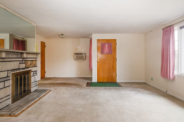 unfurnished living room featuring light colored carpet, a stone fireplace, and a wall mounted AC