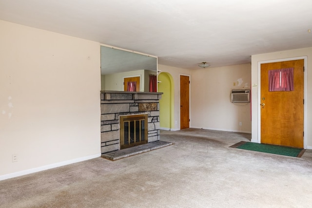 unfurnished living room featuring a fireplace, a wall mounted AC, and carpet