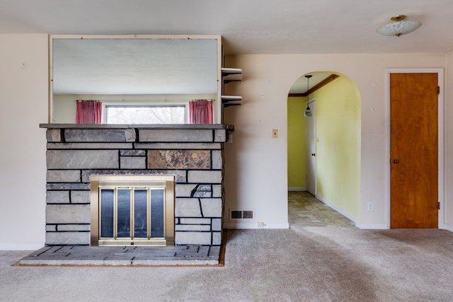 unfurnished living room featuring a stone fireplace and carpet