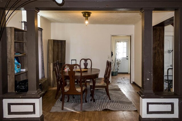 dining space featuring wood-type flooring and decorative columns