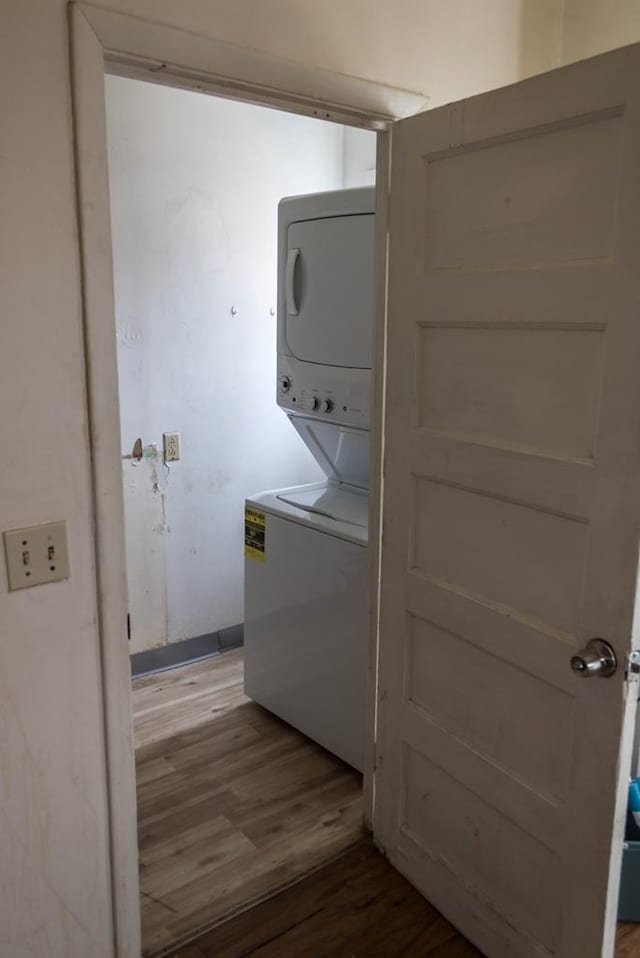 washroom featuring stacked washer / dryer and wood-type flooring