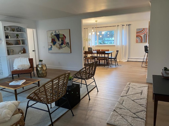 living room with baseboard heating, crown molding, a chandelier, and light hardwood / wood-style floors