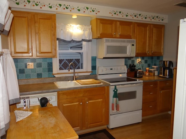 kitchen featuring sink, hardwood / wood-style floors, backsplash, and white appliances