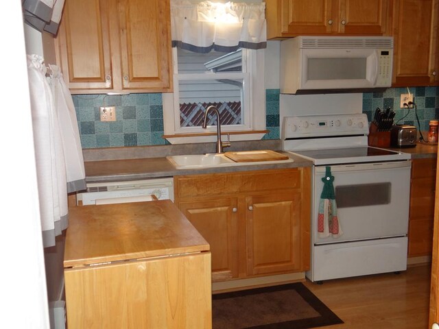 kitchen with sink, white appliances, light hardwood / wood-style floors, and backsplash