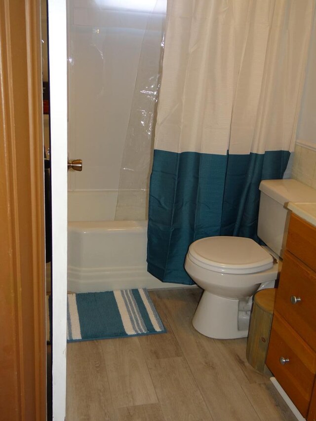 full bathroom featuring shower / tub combo with curtain, vanity, wood-type flooring, and toilet