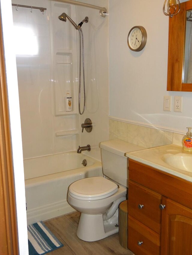 full bathroom featuring toilet, tile walls, shower / bathtub combination, vanity, and hardwood / wood-style floors