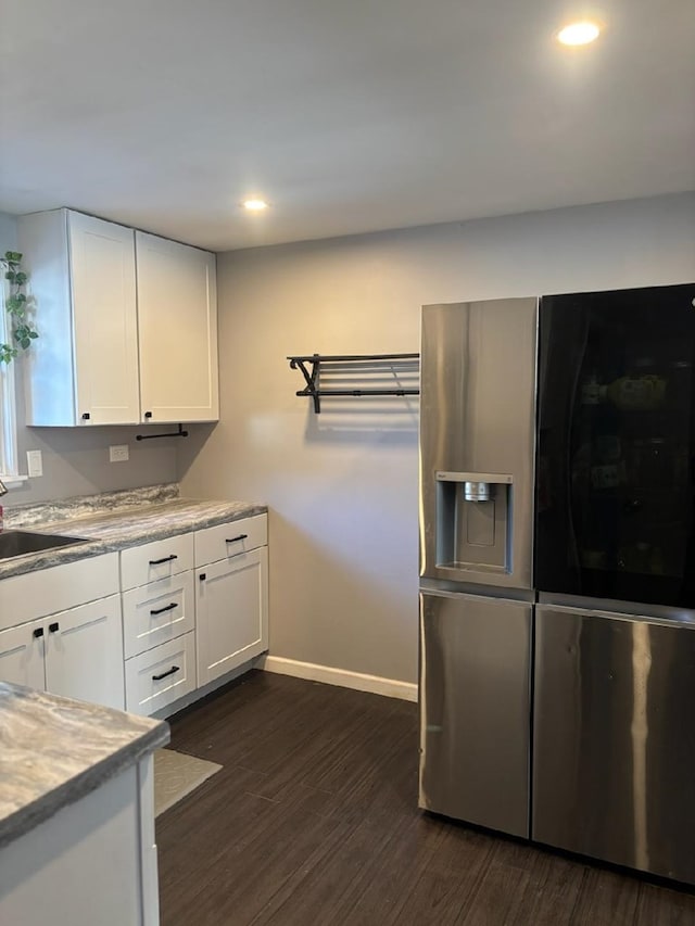 kitchen with sink, white cabinetry, light stone counters, stainless steel fridge with ice dispenser, and dark hardwood / wood-style floors