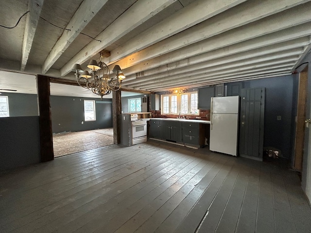 basement featuring white fridge, plenty of natural light, a notable chandelier, and light wood-type flooring