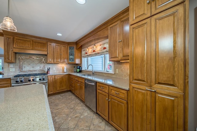 kitchen featuring appliances with stainless steel finishes, sink, backsplash, hanging light fixtures, and light stone counters