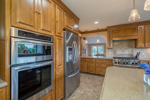 kitchen with appliances with stainless steel finishes, light stone countertops, hanging light fixtures, and backsplash