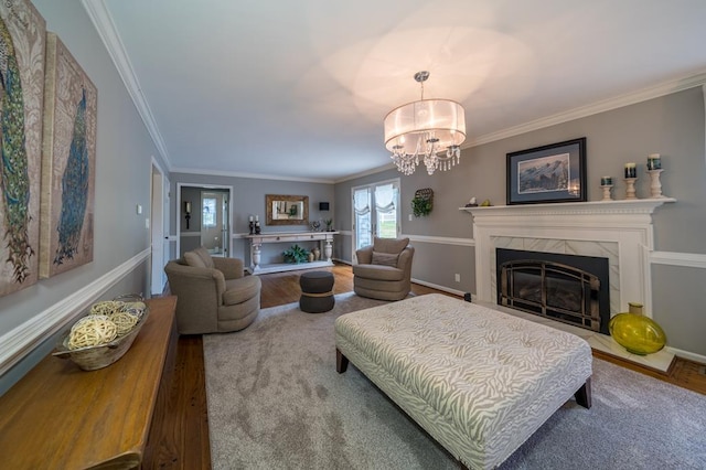 living room featuring wood-type flooring, crown molding, a notable chandelier, and a high end fireplace