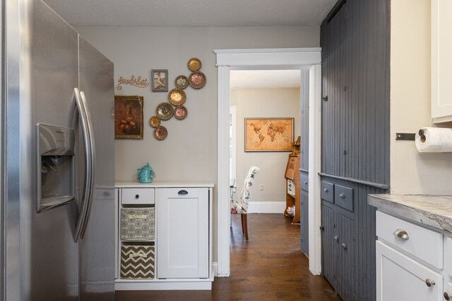 kitchen with white cabinets, dark hardwood / wood-style floors, and stainless steel fridge