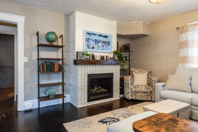 living room featuring wood-type flooring, a tile fireplace, and a textured ceiling