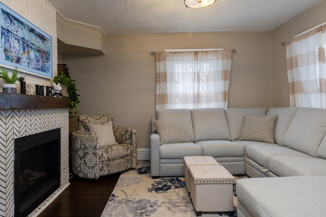 living room featuring hardwood / wood-style flooring, a tiled fireplace, and a textured ceiling