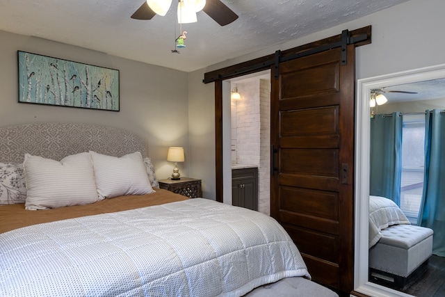 bedroom with ceiling fan, a barn door, ensuite bath, and a textured ceiling