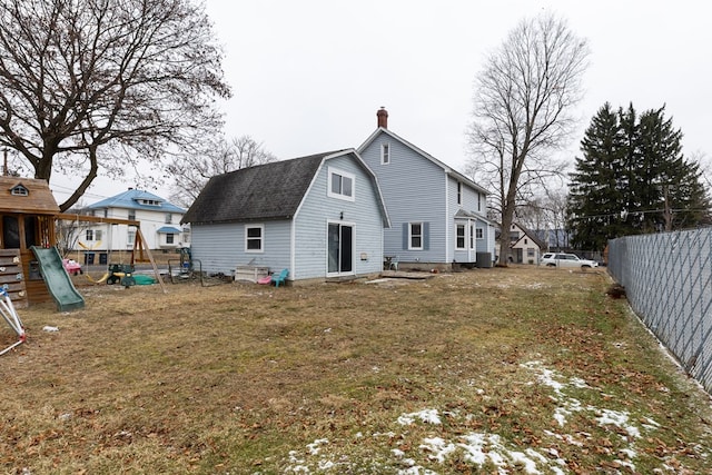 rear view of property featuring a playground and a lawn