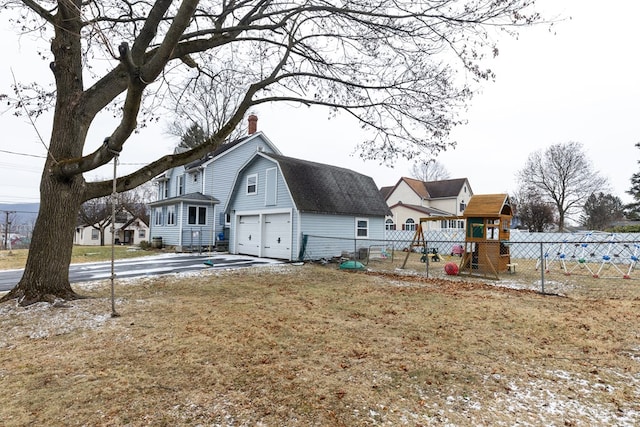 exterior space featuring a playground, a garage, and a lawn