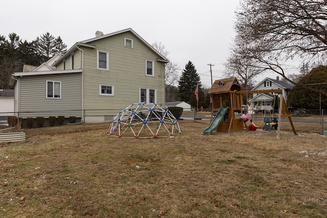 back of property featuring a playground and a lawn