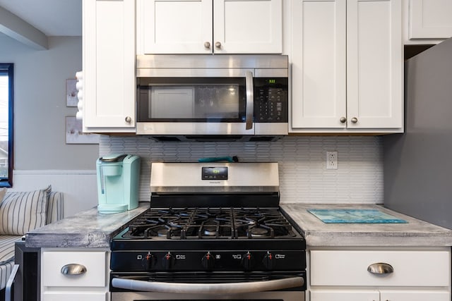 kitchen with backsplash, appliances with stainless steel finishes, and white cabinets