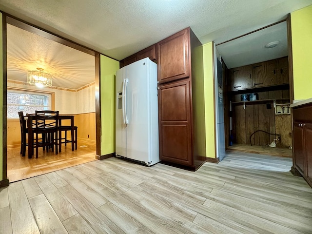 kitchen featuring white refrigerator with ice dispenser, a textured ceiling, and light wood-type flooring