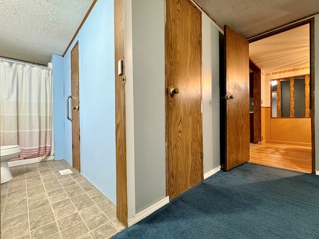 hall with carpet floors and a textured ceiling