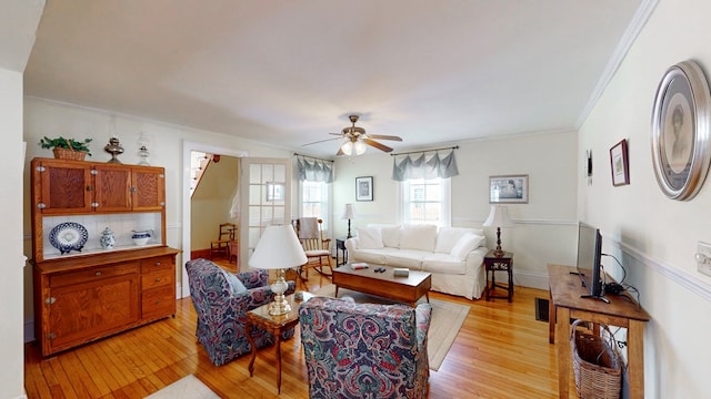 living room with ornamental molding, ceiling fan, and light wood-type flooring