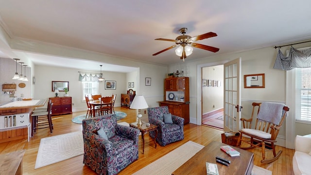 living room with ornamental molding, a wealth of natural light, ceiling fan, and light wood-type flooring