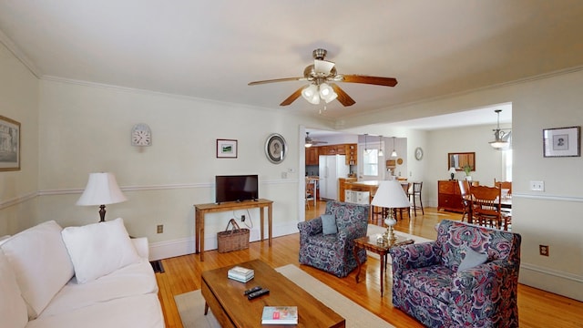 living room featuring ornamental molding, ceiling fan, and light hardwood / wood-style flooring