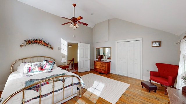 bedroom with ceiling fan, high vaulted ceiling, light wood-type flooring, and a closet