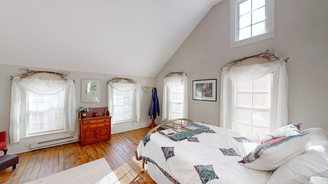 bedroom featuring multiple windows, hardwood / wood-style flooring, vaulted ceiling, and baseboard heating