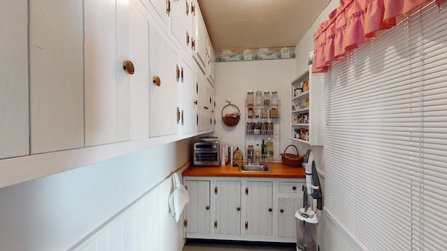 kitchen with wooden counters, sink, and white cabinets