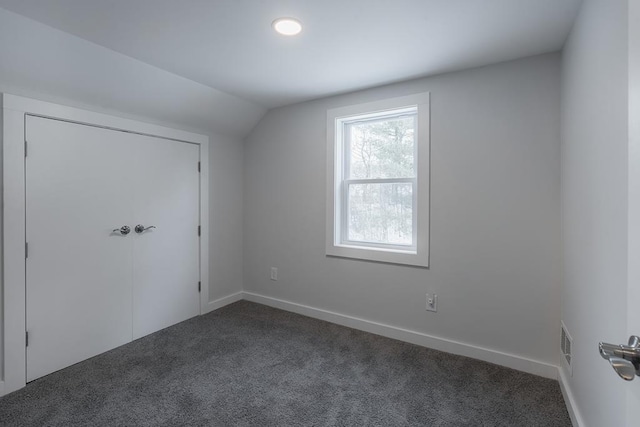 additional living space with lofted ceiling and dark colored carpet