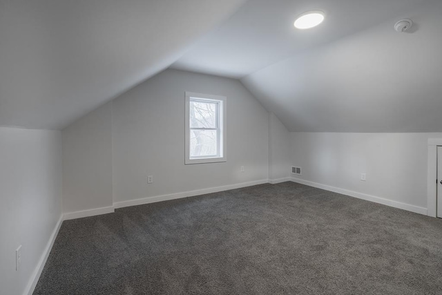 additional living space with dark carpet and vaulted ceiling