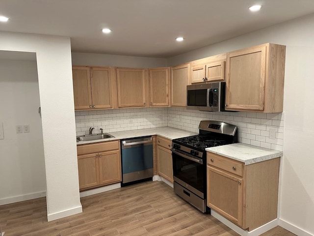 kitchen featuring appliances with stainless steel finishes, sink, light brown cabinets, and light wood-type flooring