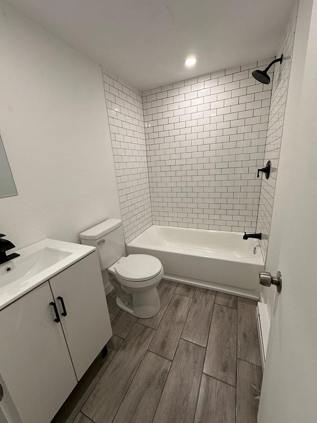 full bathroom featuring washtub / shower combination, wood finish floors, vanity, and toilet