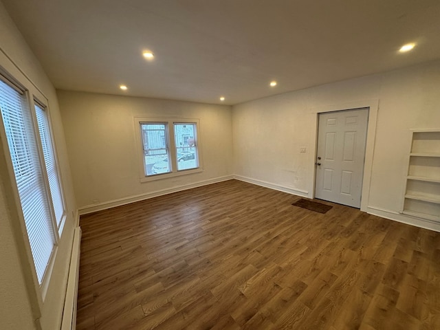 spare room featuring baseboard heating, plenty of natural light, and dark hardwood / wood-style floors