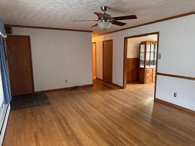 spare room featuring a baseboard radiator, ornamental molding, a textured ceiling, and light hardwood / wood-style floors