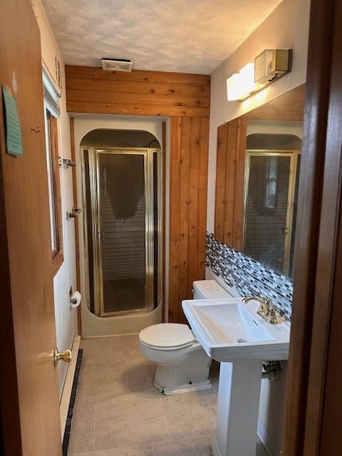 bathroom with sink, a baseboard heating unit, an enclosed shower, a textured ceiling, and toilet