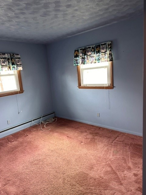 spare room with plenty of natural light, a baseboard heating unit, carpet, and a textured ceiling