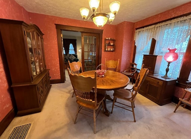 dining room with light carpet, a textured ceiling, and a chandelier