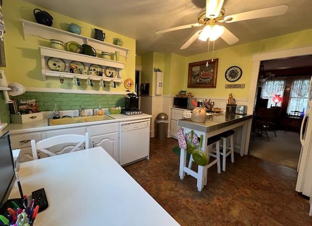 kitchen featuring sink, tasteful backsplash, white dishwasher, ceiling fan, and white cabinets