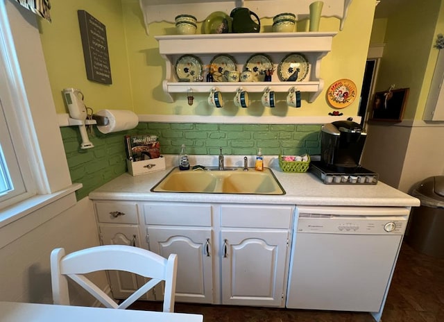 kitchen with white cabinetry, white dishwasher, and sink