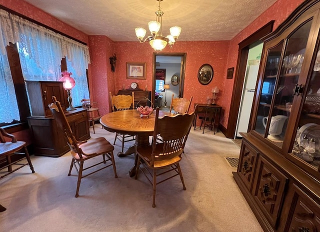 carpeted dining area with an inviting chandelier and a textured ceiling