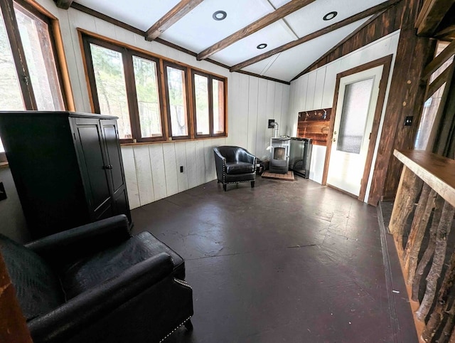 interior space with vaulted ceiling with beams and a wood stove