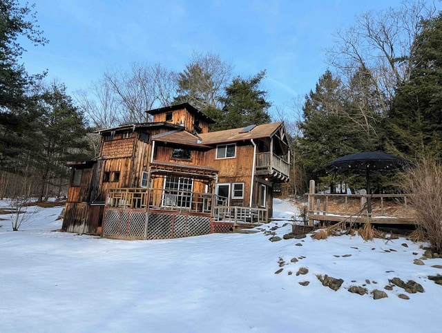 snow covered rear of property featuring a deck