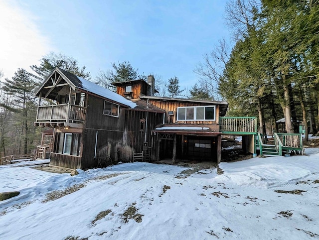 snow covered property with a balcony and a deck