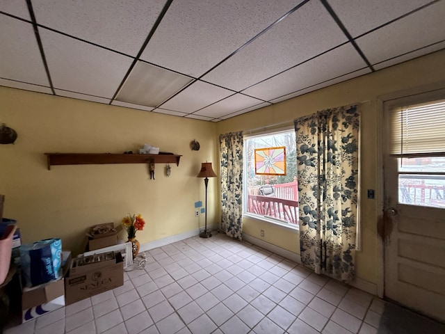 interior space with a paneled ceiling and light tile patterned flooring