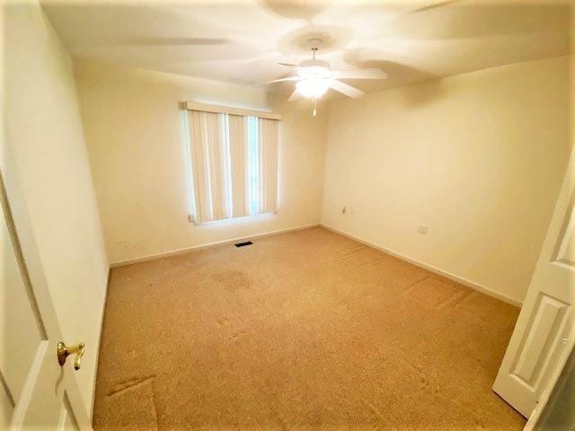 empty room featuring ceiling fan and light colored carpet