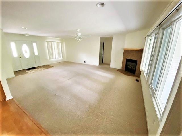 unfurnished living room featuring light carpet and ceiling fan