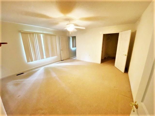 unfurnished bedroom with light colored carpet, a closet, and ceiling fan